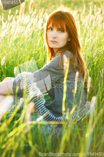 Image of sad redhead woman in grass
