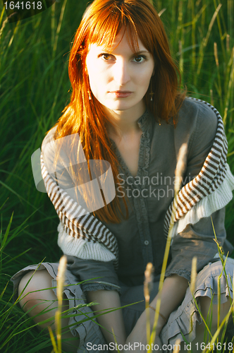 Image of sad redhead woman in grass