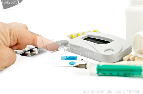 Image of Glucometer with a hand, drugs and a syringe
