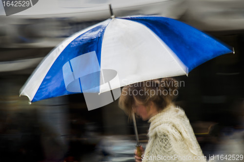 Image of Woman under blue striped umbrella