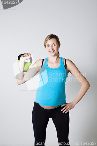 Image of Pregnant woman exercising with kettlebell