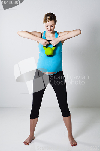 Image of Pregnant woman exercising with kettlebell