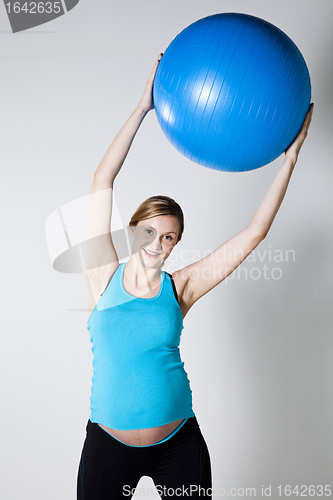 Image of Pregnant woman exercising with fitness ball