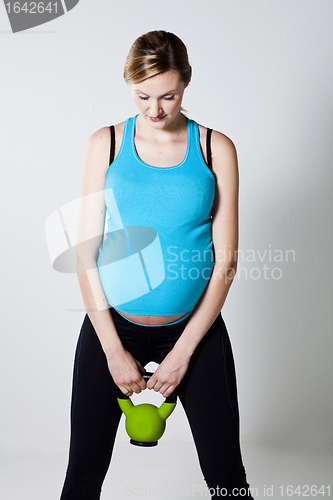 Image of Pregnant woman exercising with kettlebell