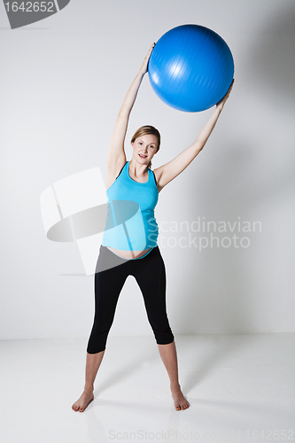 Image of Pregnant woman exercising with fitness ball