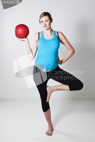 Image of Pregnant woman exercising with exercise ball while balancing