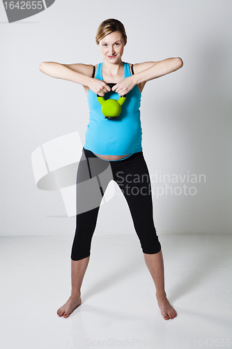 Image of Pregnant woman exercising with kettlebell