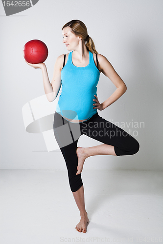 Image of Pregnant woman exercising with exercise ball while balancing