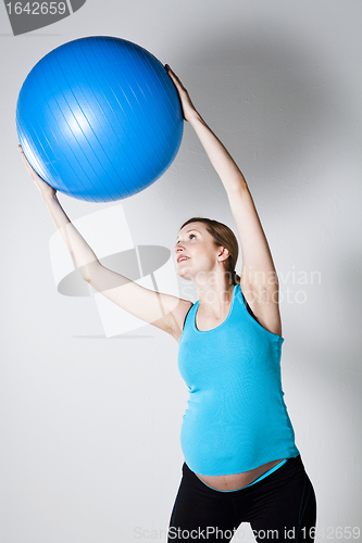 Image of Pregnant woman exercising with fitness ball