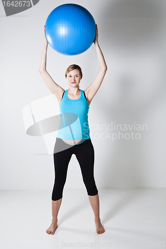 Image of Pregnant woman stretching with fitness ball