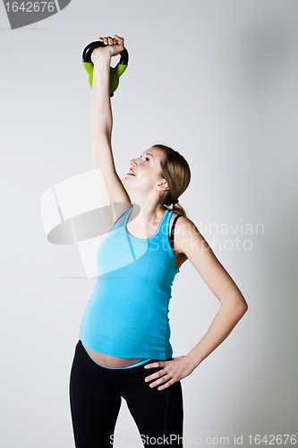 Image of Pregnant woman exercising with kettlebell