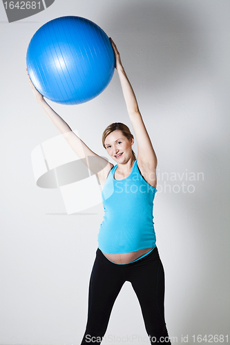 Image of Pregnant woman exercising with fitness ball