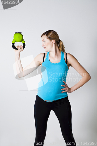 Image of Pregnant woman exercising with kettlebell