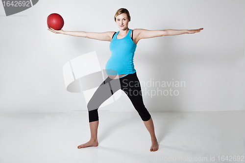 Image of Pregnant woman exercising with exercise ball