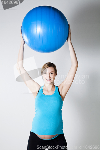 Image of Pregnant woman stretching with fitness ball