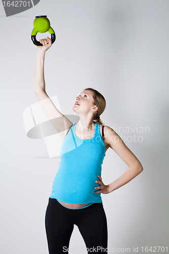 Image of Pregnant woman exercising with kettlebell