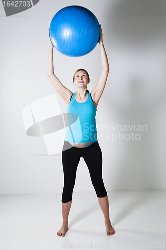 Image of Pregnant woman stretching with fitness ball