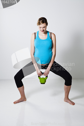 Image of Pregnant woman exercising with kettlebell