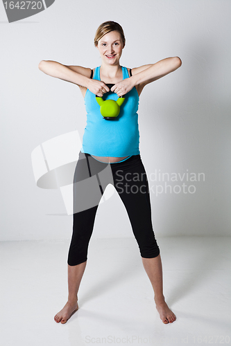 Image of Pregnant woman exercising with kettlebell