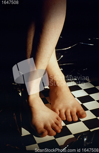 Image of Feet of a woman on chess board with black background
