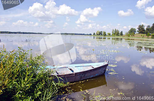 Image of Spring lake fragment. Old boat moored on shore. 