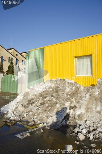 Image of pile of melting snow in spring near building 