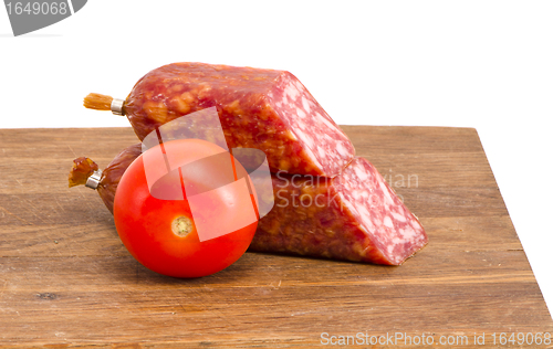 Image of cut smoked sausage pieces and tomato cutting board 