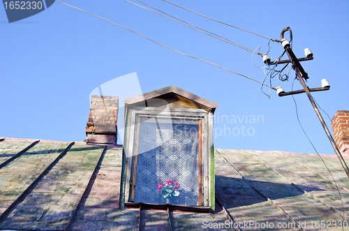 Image of Ancient rural house tin roof attic window chimneys 