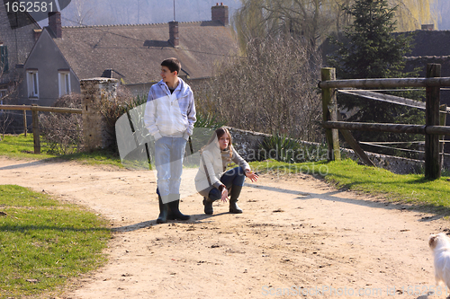 Image of a boy and a girl playing with a dog in the countryside