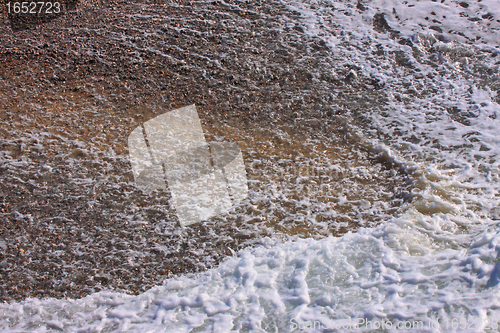 Image of wave and foam on a pebble beach in Etretat