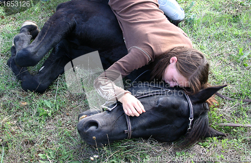 Image of horse laid down and riding girl