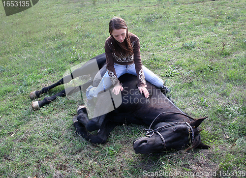 Image of horse laid down and riding girl