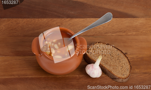 Image of Soup in clay pot with bread and garlic