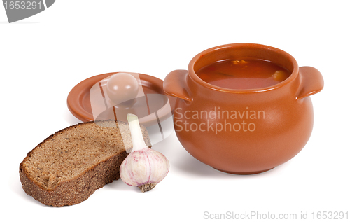 Image of Soup in clay pot with bread and garlic