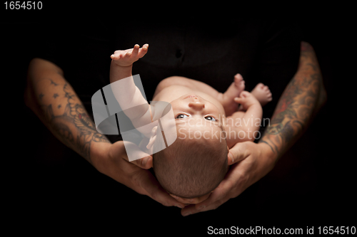 Image of Hands of Father and Mother Hold Newborn Baby on Black