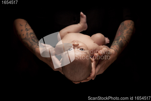 Image of Hands of Father and Mother Hold Newborn Baby on Black