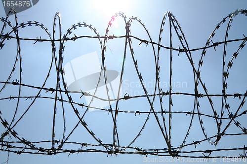 Image of barbed wire against blue sky 