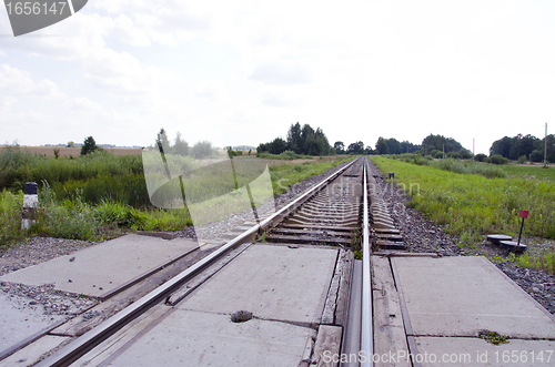Image of Railway track cross road between fields and forest 