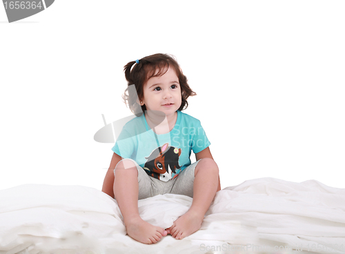 Image of Curly toddler girl in bed, looking into camera 