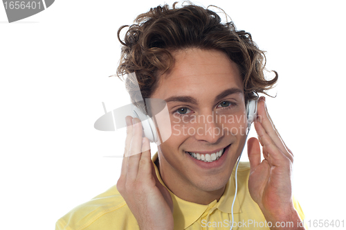 Image of Casual young man listening music with headphones