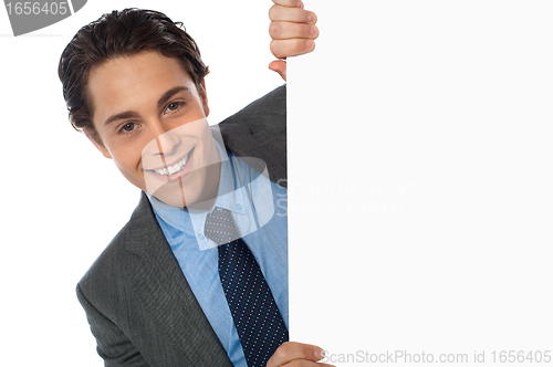 Image of Businessman peeking behind a whiteboard