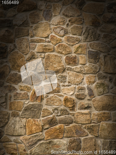 Image of Brown masonry rock wall lit dramatically 