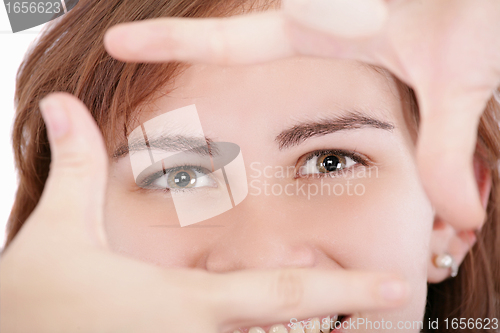 Image of Pretty adult woman looking through a frame made by her hands.