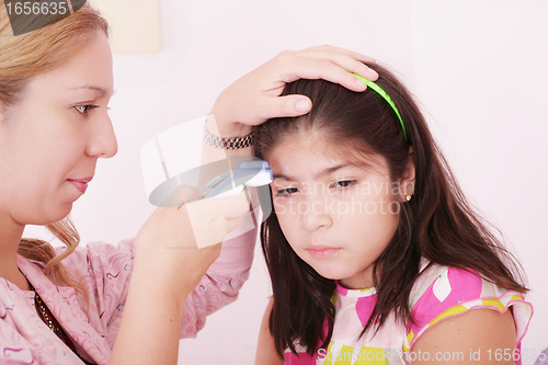 Image of Portrait of a sick child being checked with a thermometer by a d