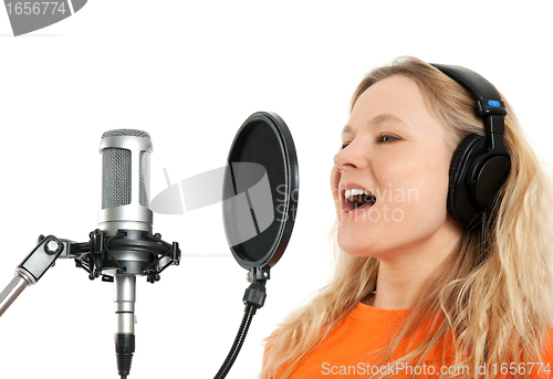 Image of Girl in headphones singing with studio microphone
