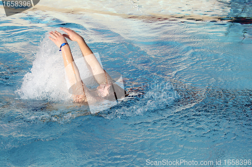 Image of young man swimming backstroke in pool