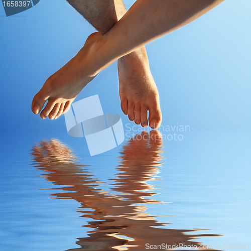 Image of female and male foot in blue water  