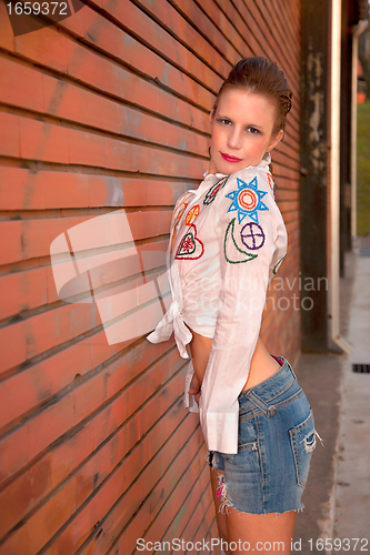 Image of beautiful and sexy middle-age woman, leaning against a brick wall