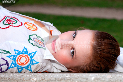 Image of beautiful middle-aged woman, lying on a garden bench