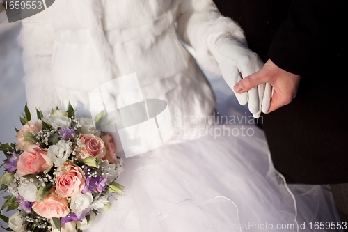 Image of hands of groom and bride with wedding bouquet